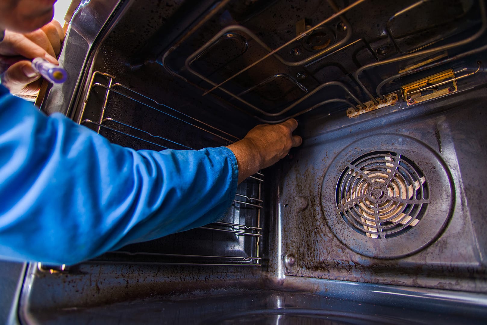 - Sam's Appliance Repair Profesional handyman fixing the motor fan in the oven
