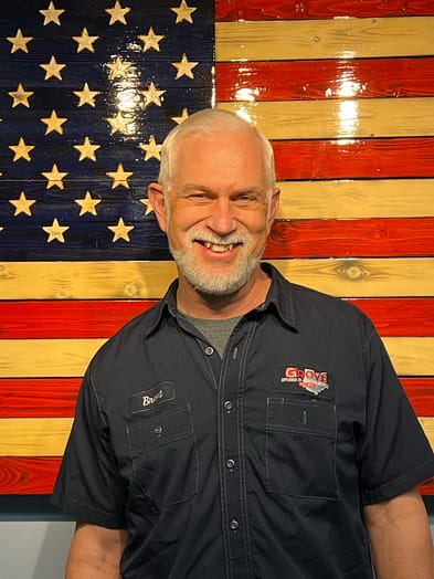 appliance-repairman-brent Appliance repairman smiling while standing in front of an American Flag.